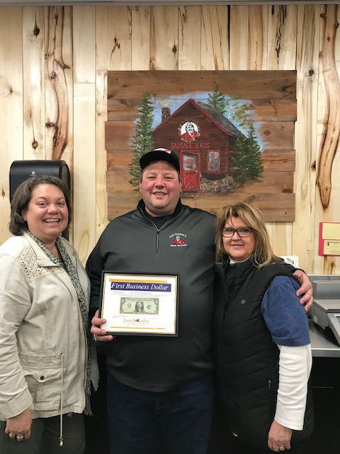 Pictured are owner Ben VonBank and Manager Paula Benusa receiving their First Business Dollar from Chamber representative Roxie Parks (left).