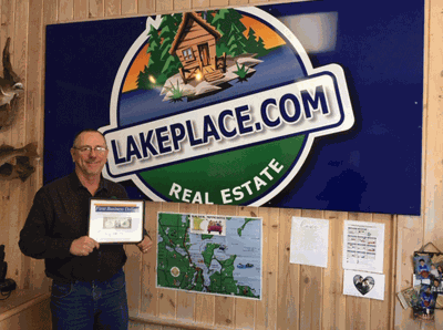 Pictured is Jim Flesch holding the First Business Dollar. Angie Schultz is also a realtor with LakePlace.com/Walker