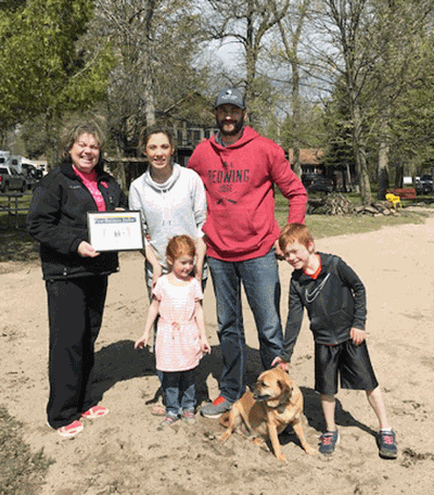 Chamber employee Roxie Parks (left) hands the Eckart family their First Business Dollar.