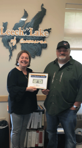 Board member Kevin Merten receives the First Business Dollar from Chamber employee Roxie Parks.
