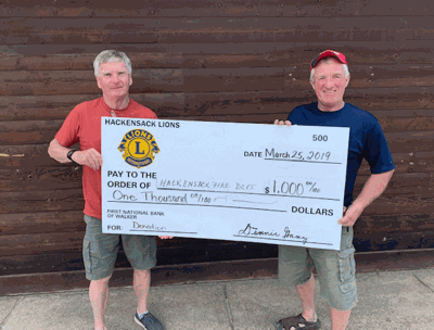 Lion Jim Tuller (left) hands the “big check” to Chief Tony Peterson