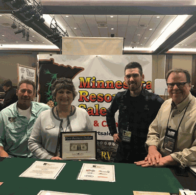 Leech Lake Chamber Executive Director Cindy Wannarka presents the First Business Dollar to (from left) Associate Broker Dan Houle of the Walker Area North office, Broker Mike Anderson and Sales Agent Ross Coyer.