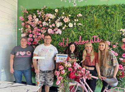 Pictured is (from left) employee Christine Greenawalt, owners Luke and Alise McGregor holding the First Business Dollar, and employees Maya Ravenhorst and Zoe Taatjes.