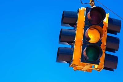 A yellow traffic light with a sky blue background