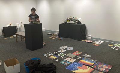 Portage High School art teacher Lorisa Harvey, with assistance from teacher Stacie Flocca, prepares for the 2026 student art exhibit at the Portage Center for the Arts in the Drury Gallery on May 6.
