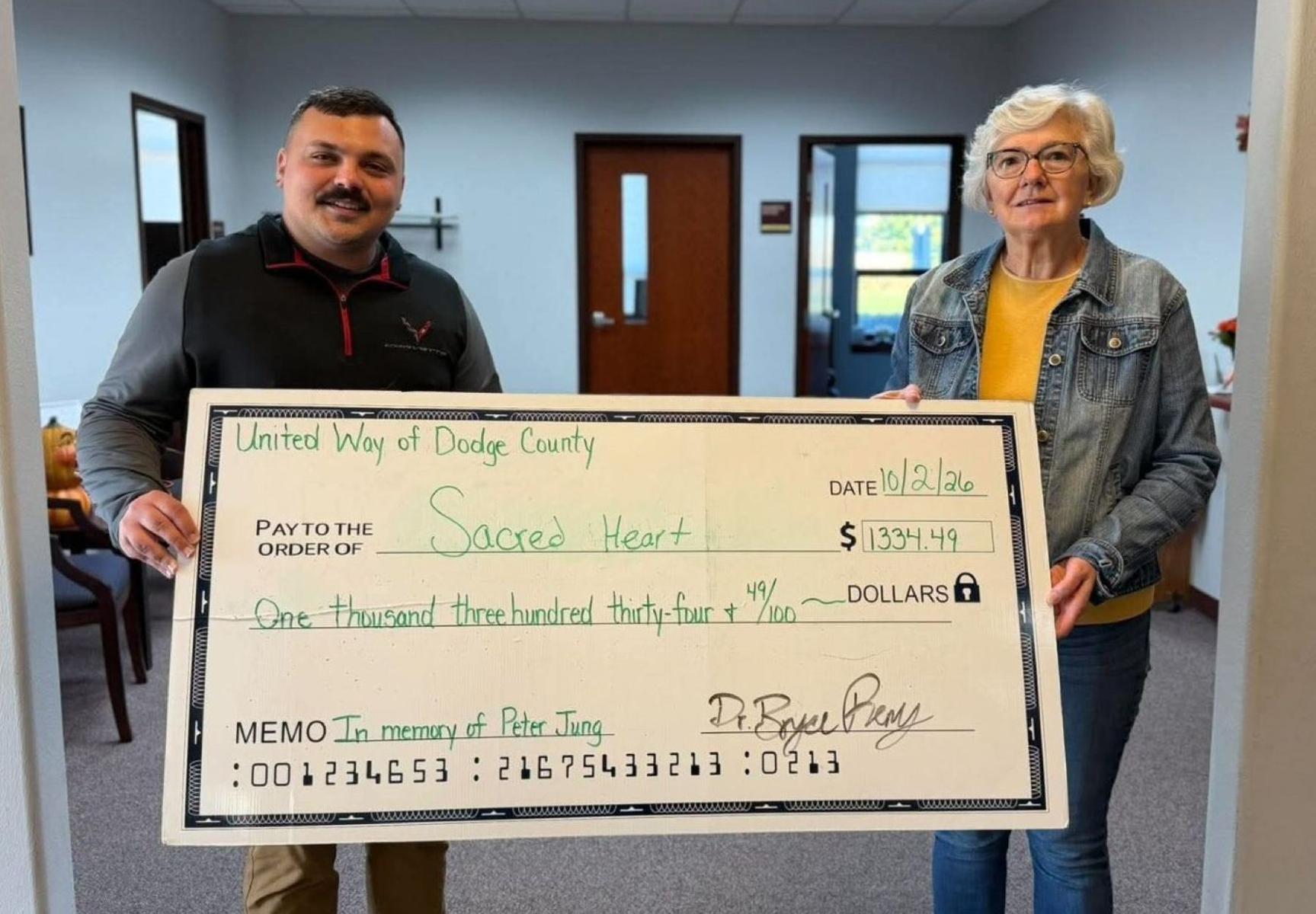 Bryce Remy, president of United Way of Dodge County, left, presents Luann Bogenschneider, Sacred Heart Food Pantry volunteer, with a $1,334.49 donation on Oct. 2.