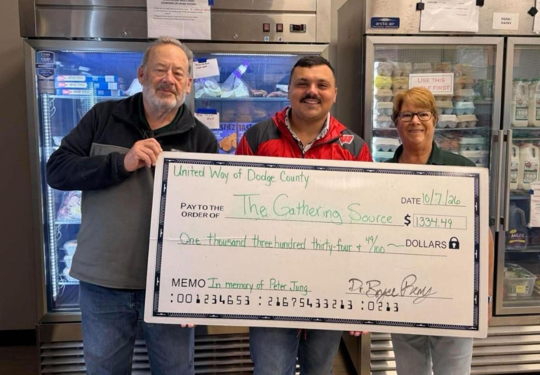 Bruce Wadman, The Gathering Source president, left, and Sally Drenoske, pantry operations manager, right, accept a $1,334.49 donation from Bryce Remy, United Way of Dodge County president, on Oct. 7.