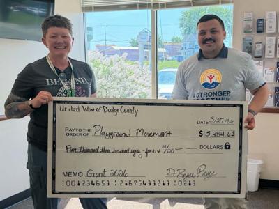 Bryce Remy, United Way of Dodge County president, right, presents Laura Goral, Playground Movement, a $5,384.61 donation on May 27.