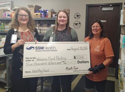 Terri Respalje, right, manager of the Waupun Food Pantry, accepts a $5,000 Community Health grant from SSM Health Waupun Memorial Hospital l's leaders, Nicole Gill and Alex Gago, to support food insecurity initiatives in the Waupun area on Aug. 8.