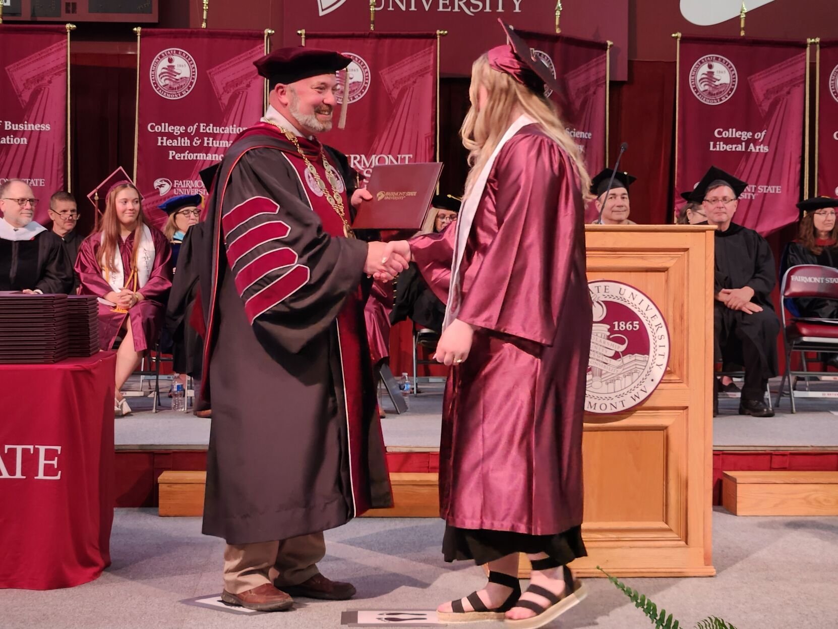 A Fairmont State University graduate receives her diploma from university president Dr. Mike Davis.